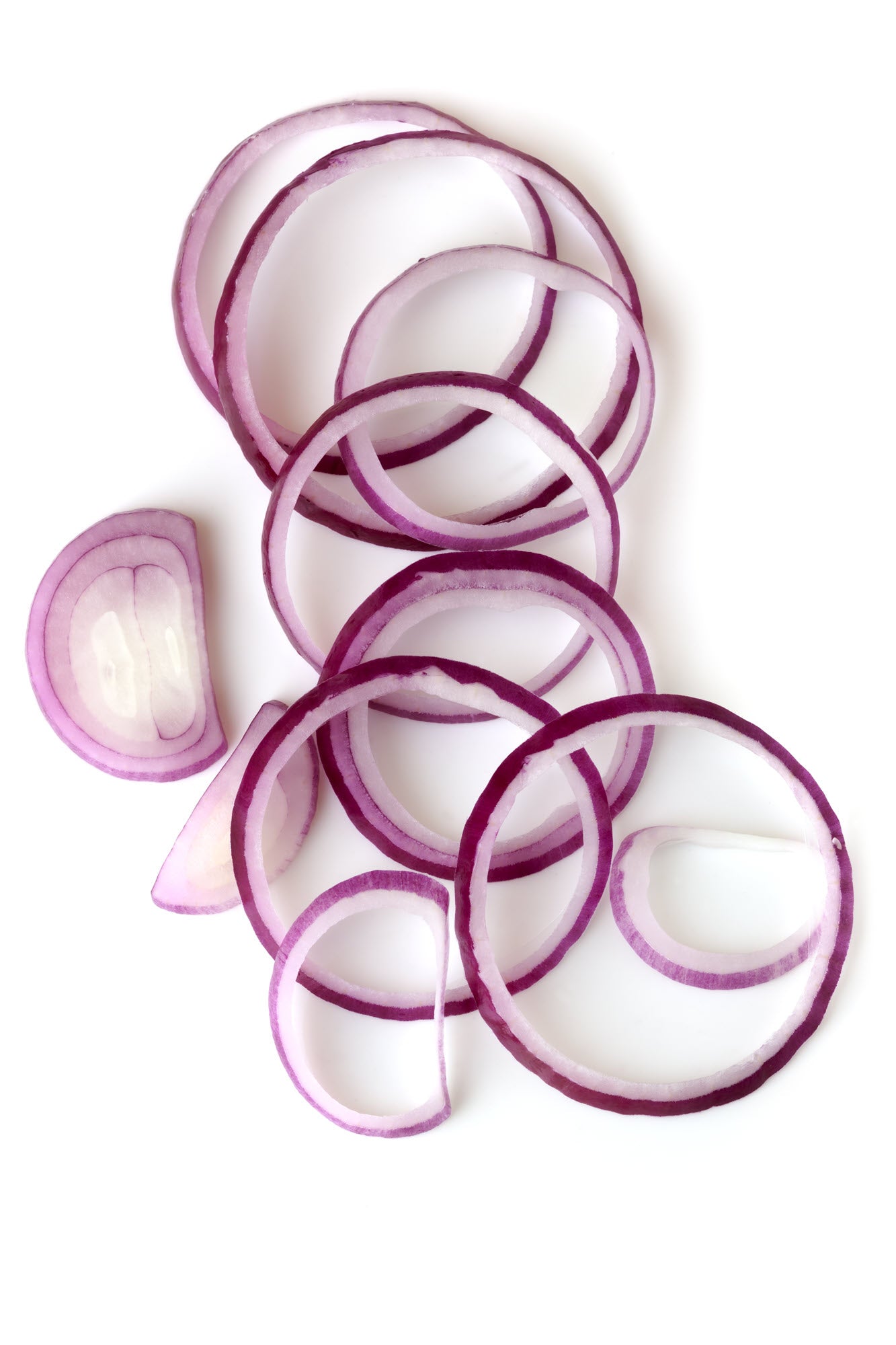 On display are slices of red onions, of the variety Short Red Creole. The red onion slices are loosely laid from north to south, overlapping each other.  The red onion slices are displayed on a pure white surface, and viewed from above. 